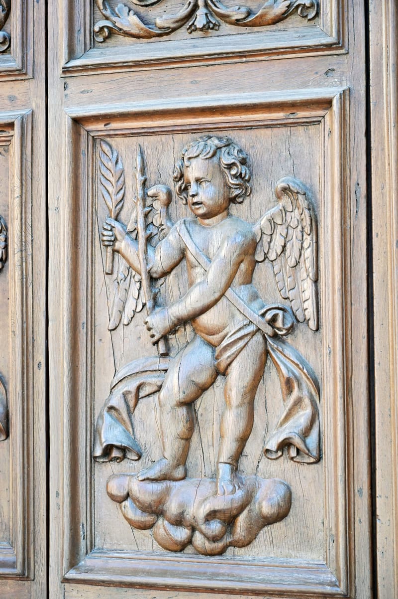 Dettaglio della porta della facciata minore: figura alata scolpita